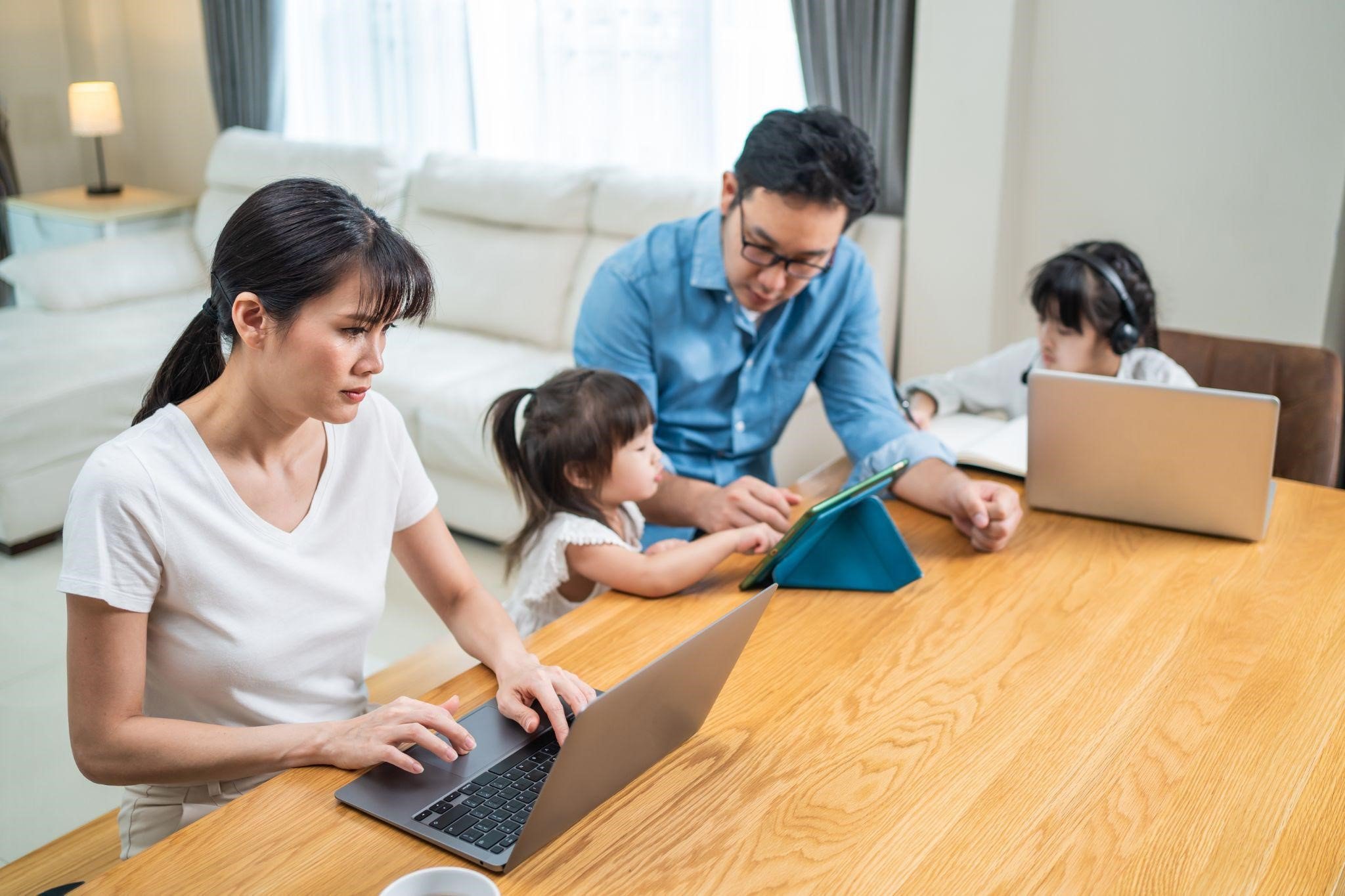 Remote-working parents assisting their young daughter with online learning at home.jpg
