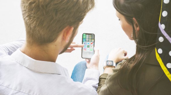 friends-using-application-mobile-phone-by-connecting-with-smart-watch.jpg