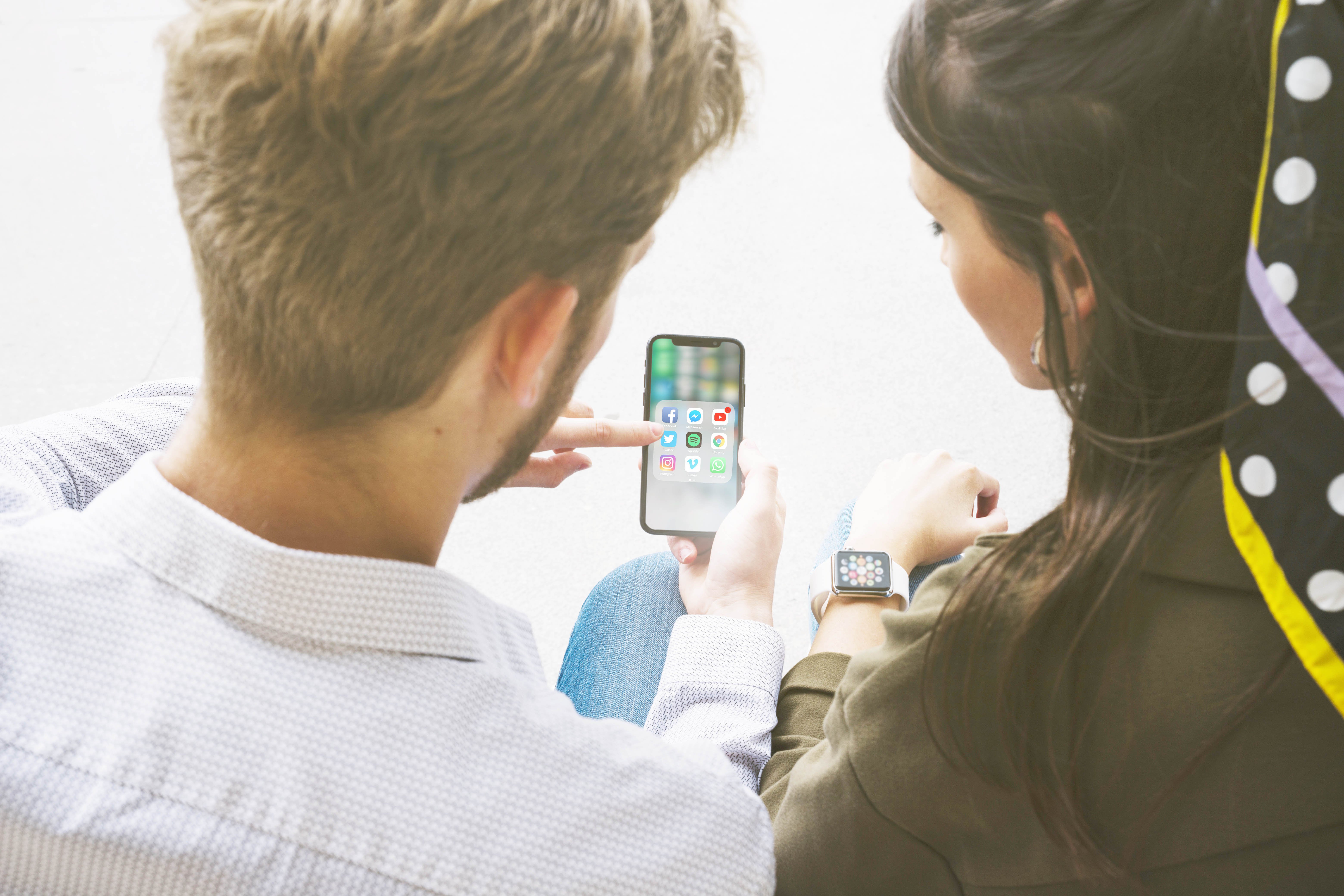 friends-using-application-mobile-phone-by-connecting-with-smart-watch.jpg