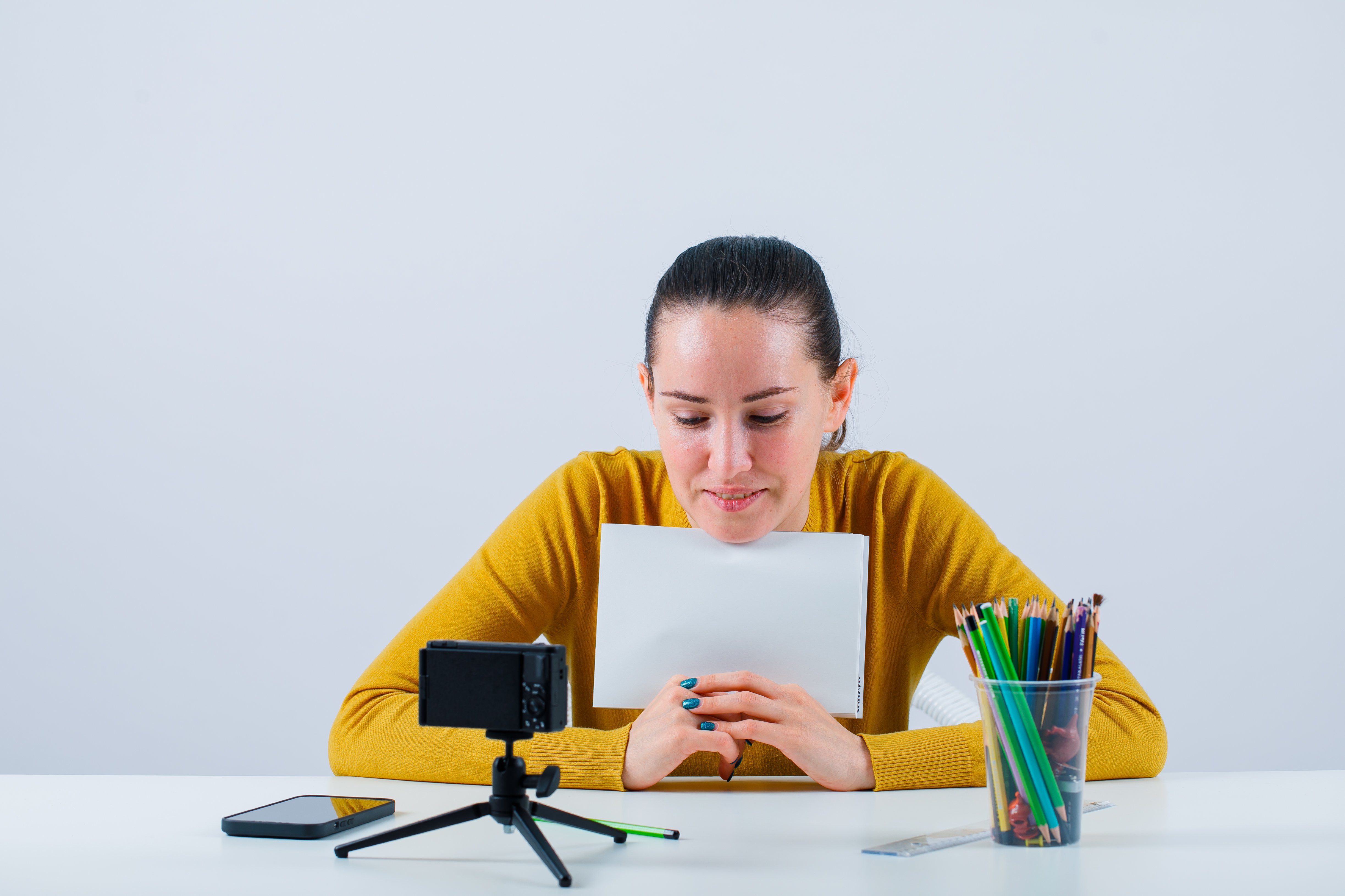 smiling-blogger-girl-is-showing-mockup-idea-with-paper-white-background.jpg